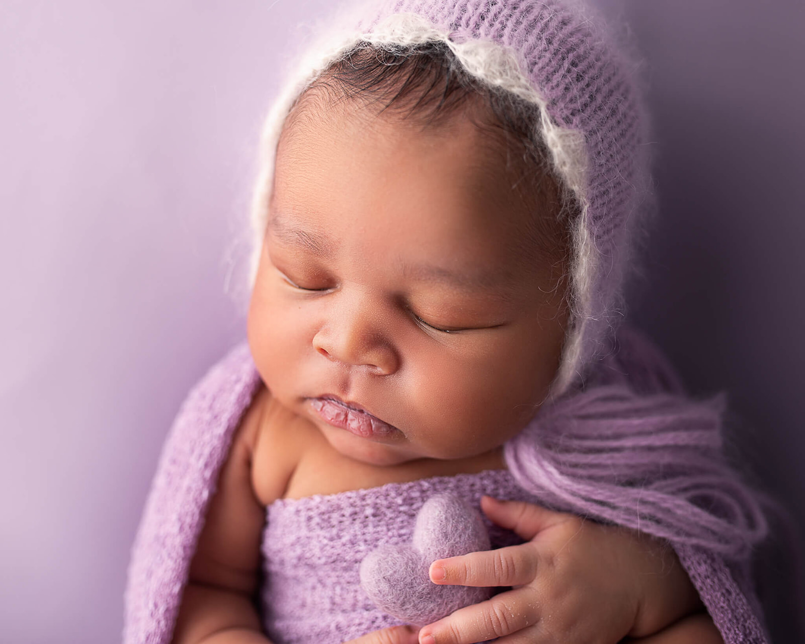 newborn photo wrapped in purple outfit on a purple background during Akron OH newborn photoshot