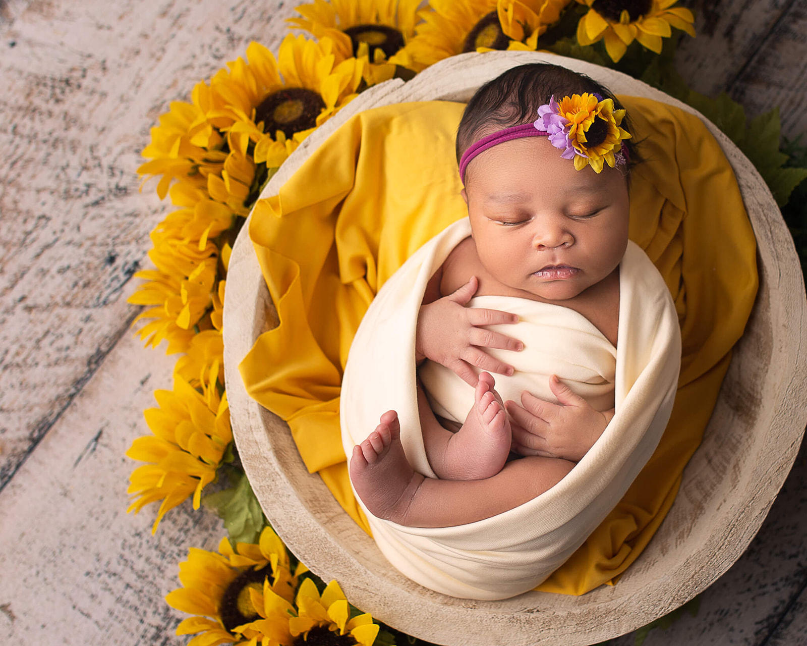 newborn baby in a basket surrounded by sunflowers during Akron OH newborn photoshoot