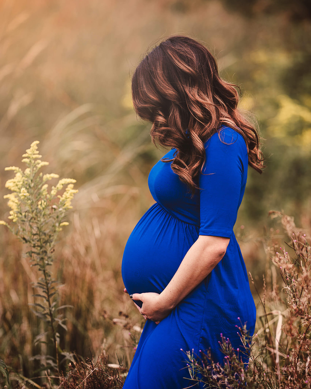 pregnant woman in a blue dress outside in a field