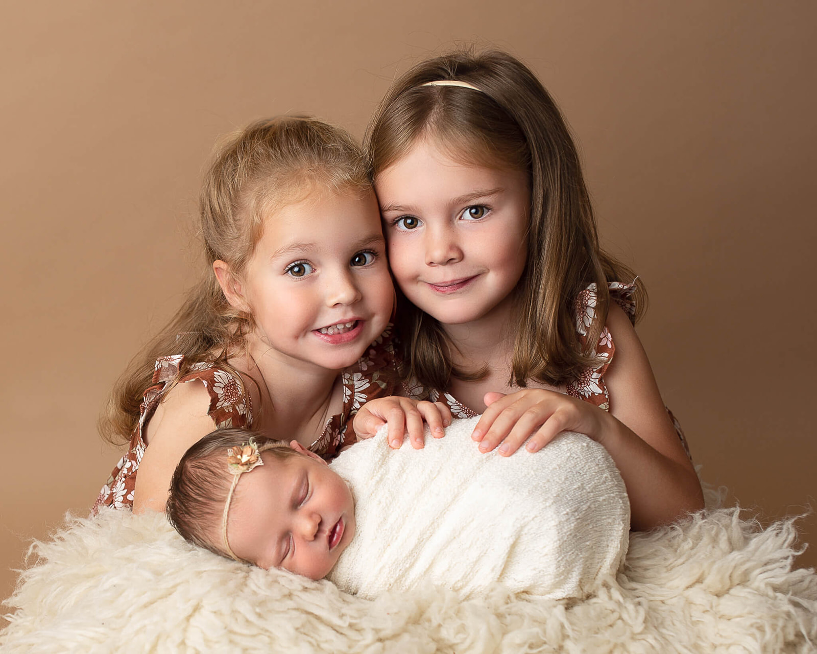two young girls smiling with their sibling. how to prepare your toddler for a newborn