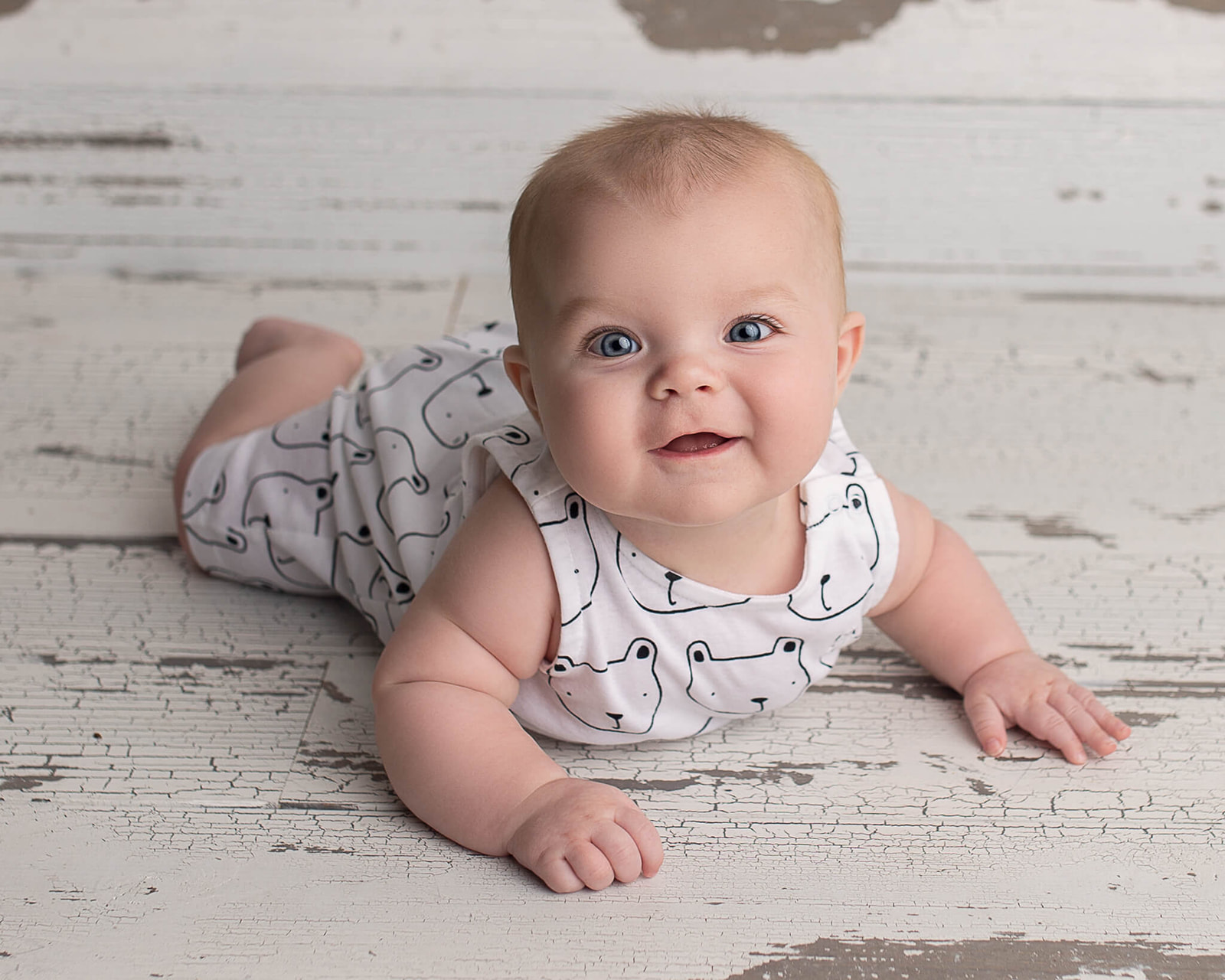 6 month old smiling on belly during newborn session for introducing solid foods to your baby