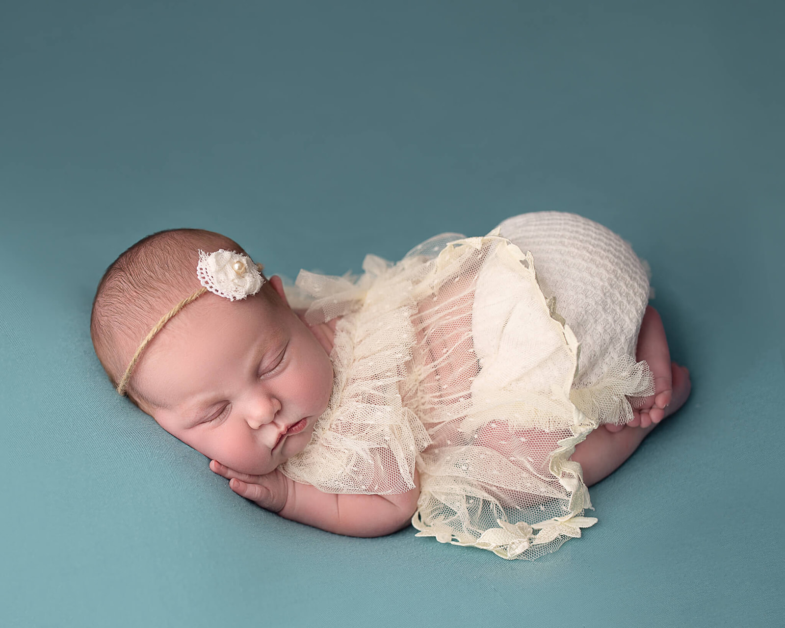 newborn dressed in cream colored mesh top and cloth bottom sleeping during newborn photography session. Newborn care tips