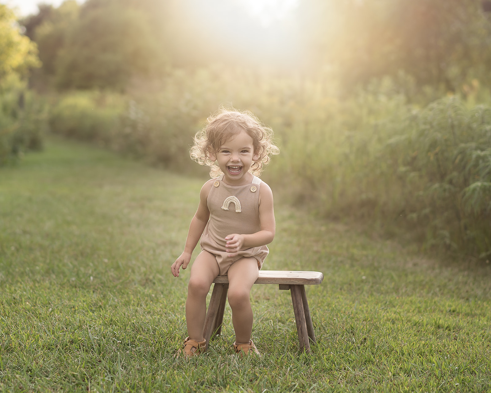 little girl sitting on bench in open field