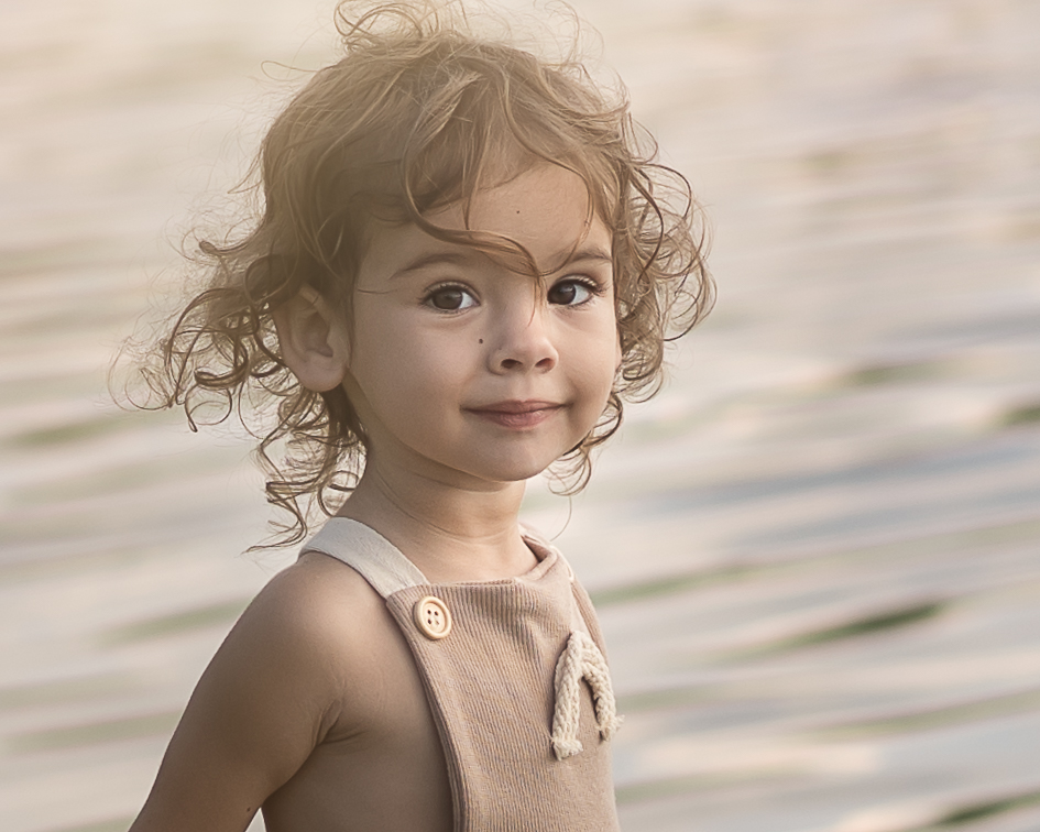 close up of little girl with tan dress and blurred water background for best preschools in Akron OH article