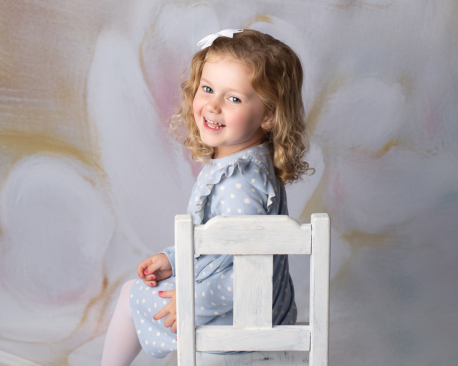 smiling girl in white chair and blue dress