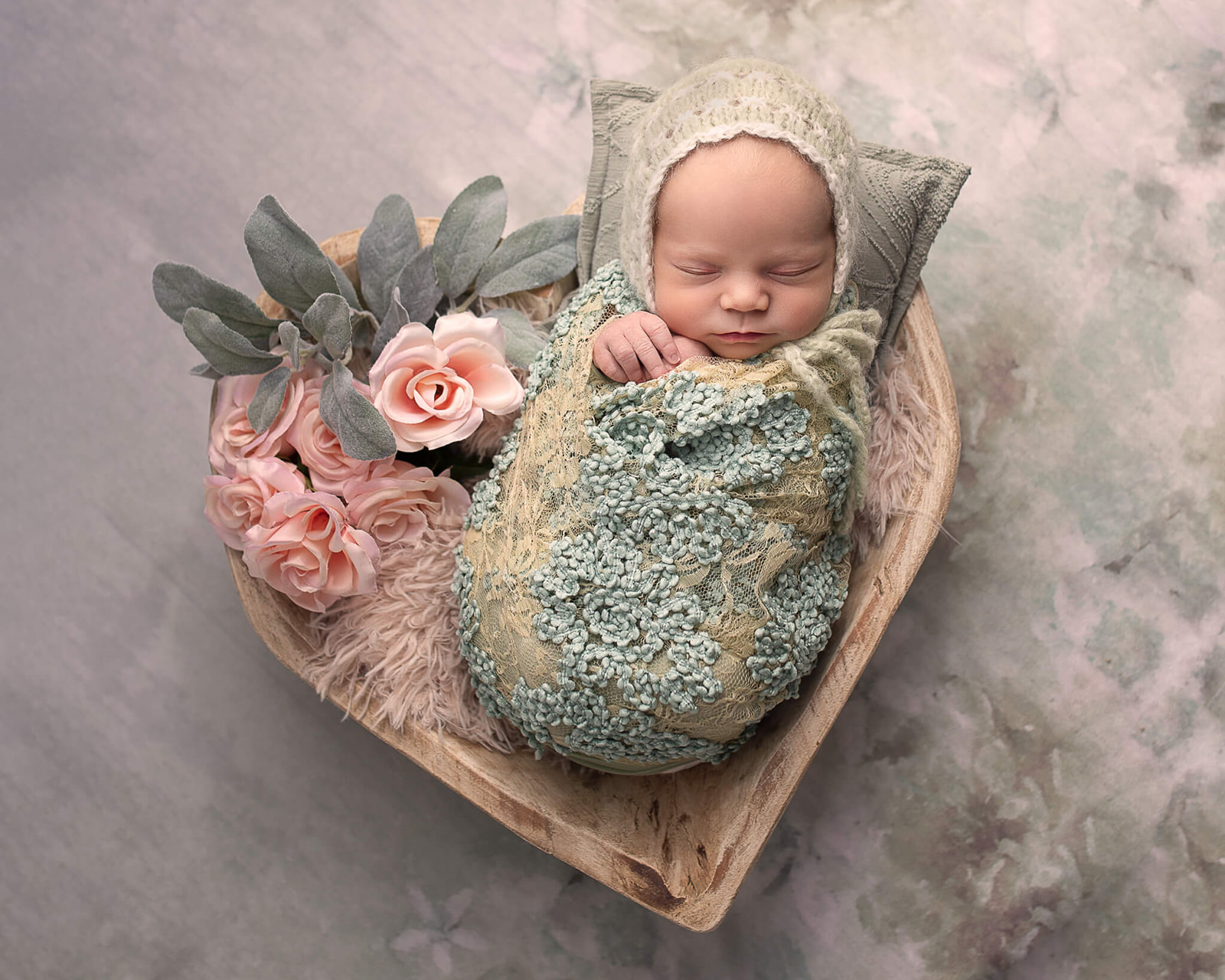 newborn in a wrap on a heart shaped board for best doulas in Akron OH article