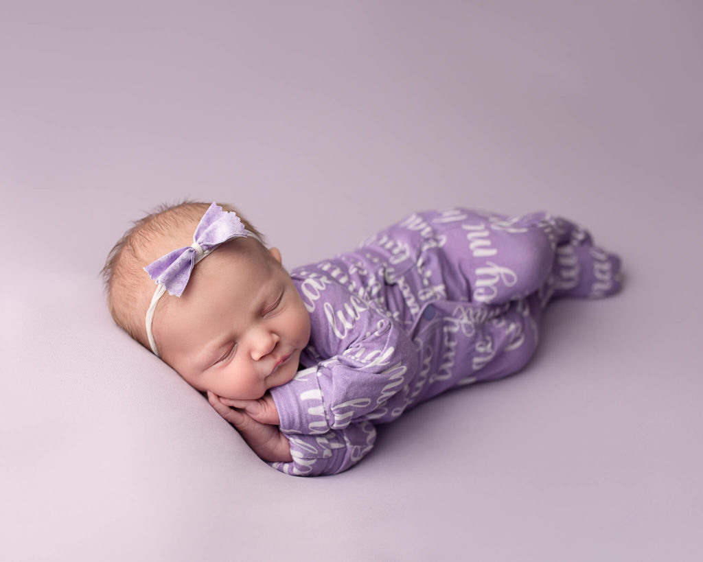 newborn in purple onesie sleeping 