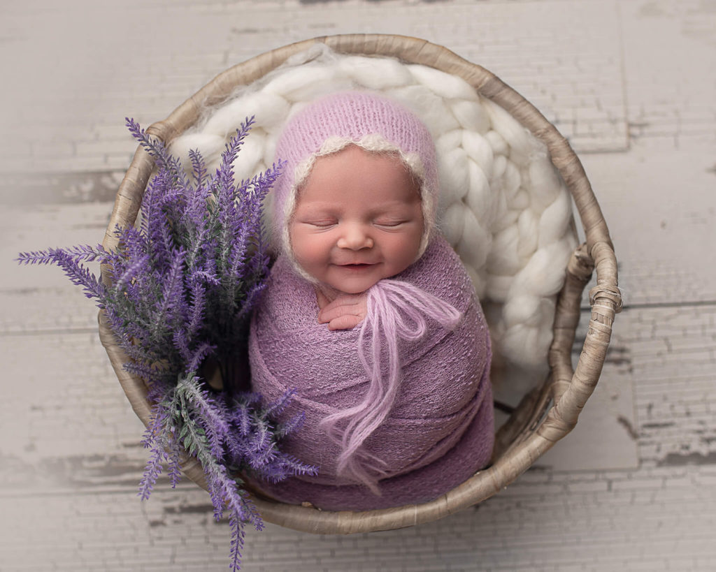 In blog photo of sleeping, smiling newborn in basket for pediatric occupational therapy blog
