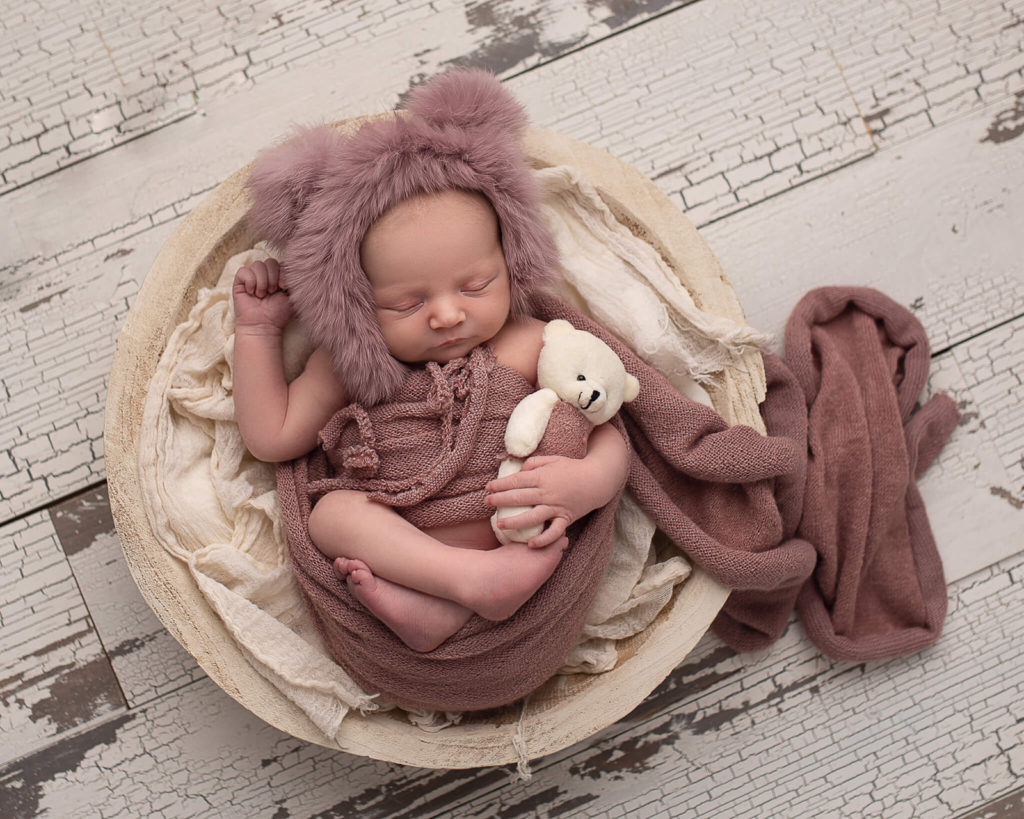 In blog photo of sleeping newborn in bear hat and basket for pediatric occupational therapy blog