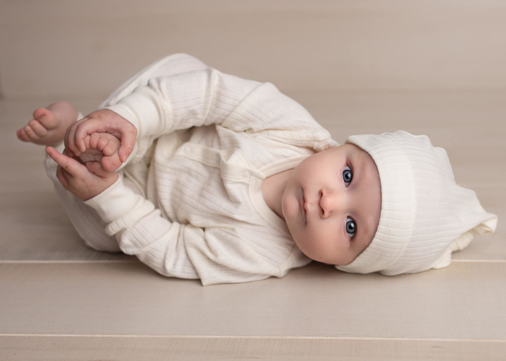 Akron winter activities with kids in blog photo of newborn in cream onesie and hat laying on side