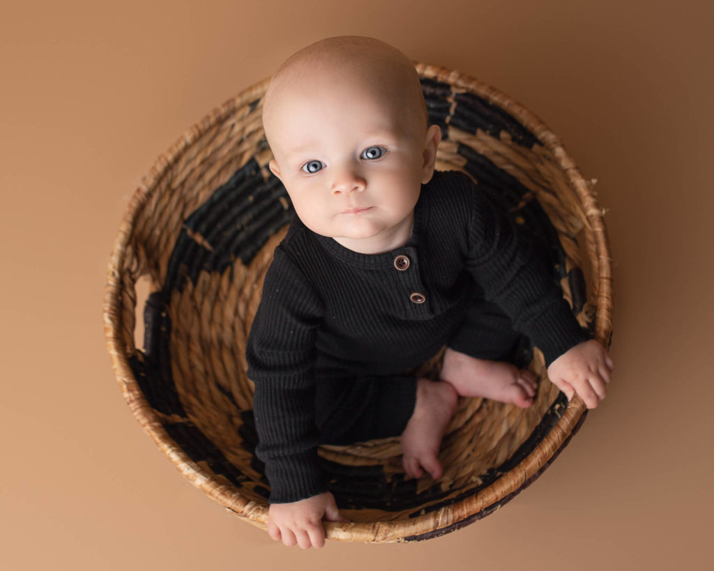 pediatric speech therapists in akron OH in blog photo of baby in black outfit sitting in a beautiful basket looking at camera
