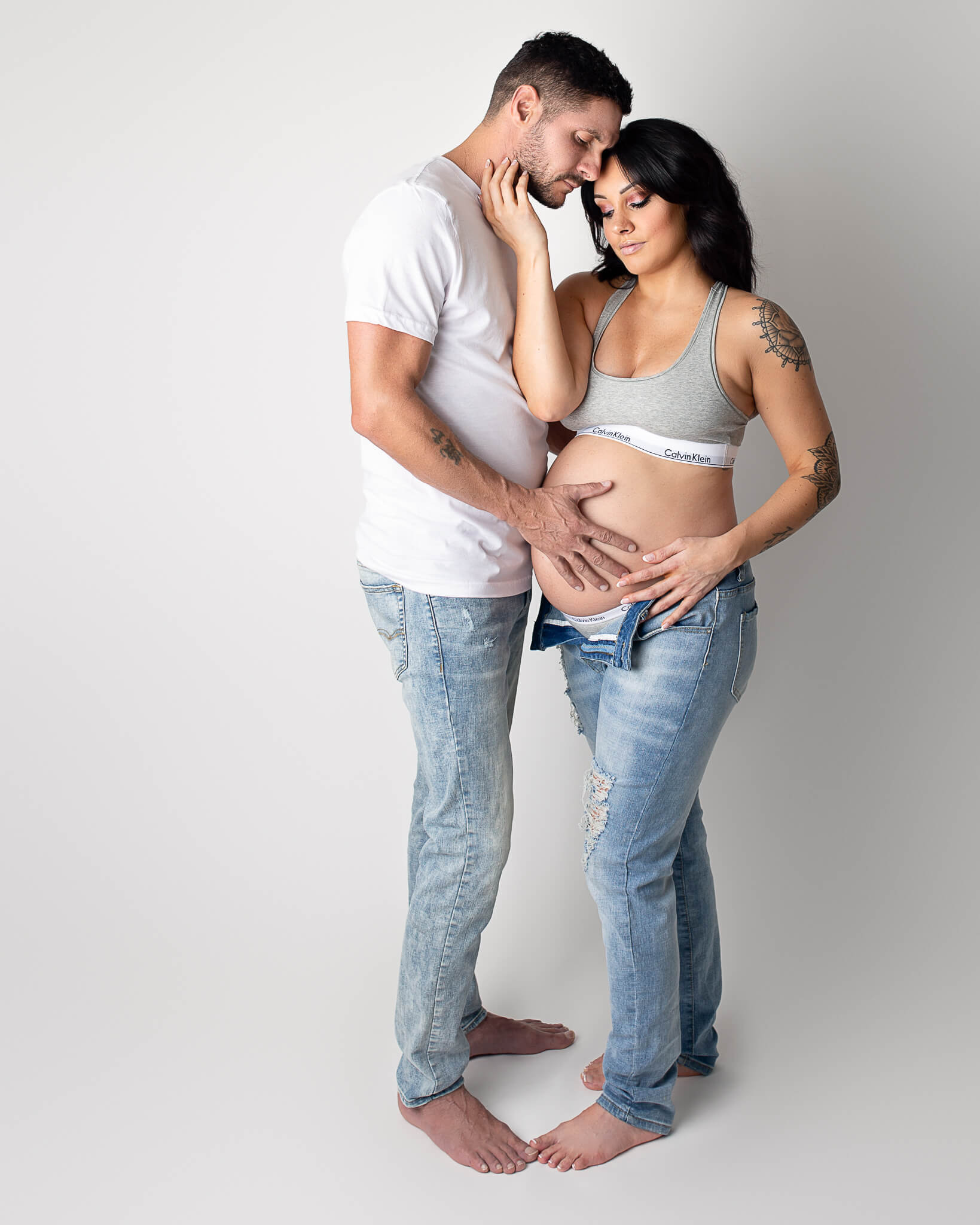 connecting with your baby in the womb in blog photo of pregnant mother and father in casual clothes embracing each other