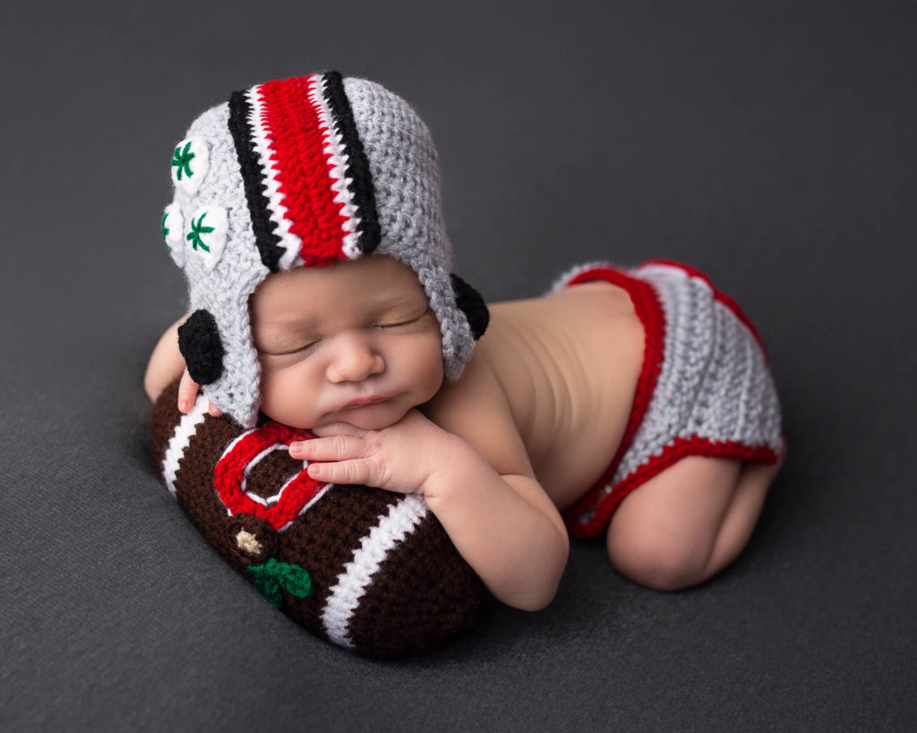 pediatric physical therapists in akron in blog photo of sleeping newborn in football outfit