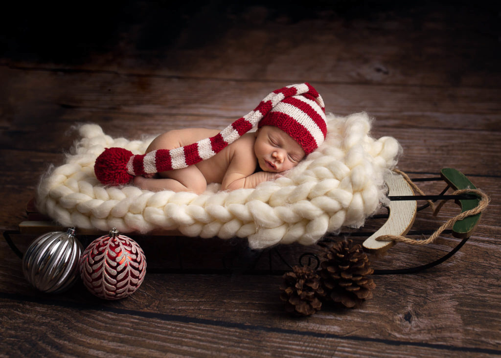 photo of sleeping newborn on blanket sleigh with stripe d santa hat for signs your baby needs ABA therapy blog