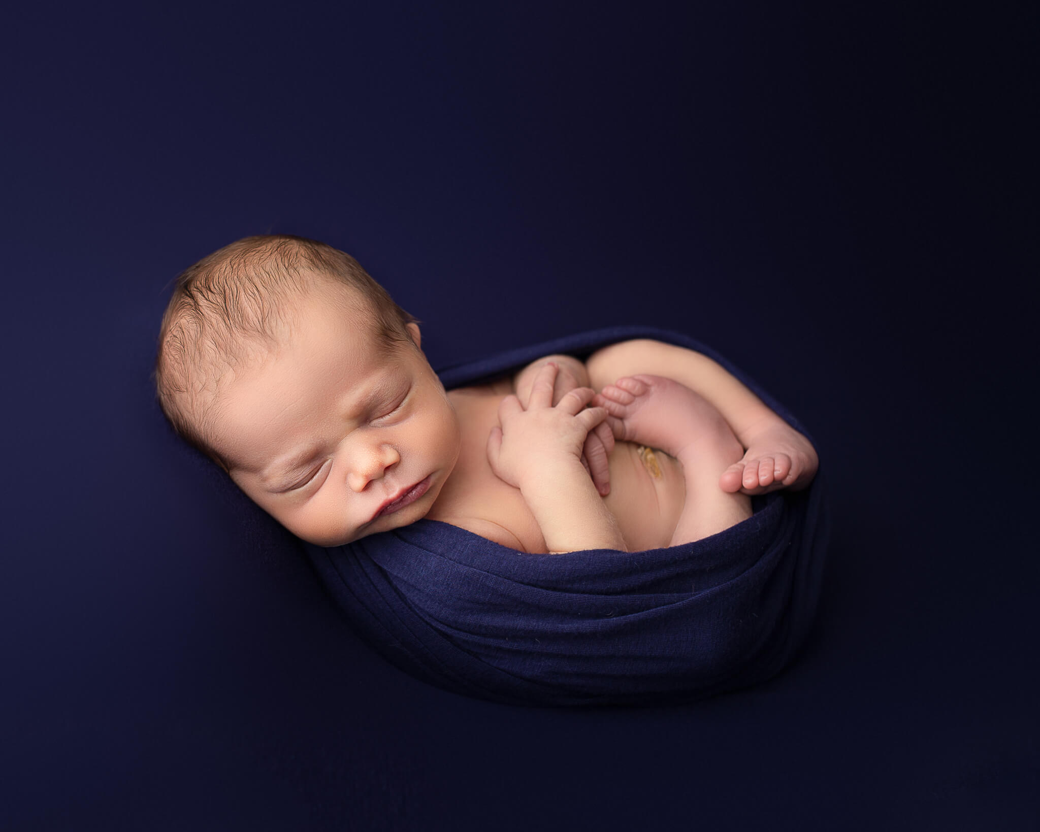 guide to newborn care in blog photo of newborn in navy blanket