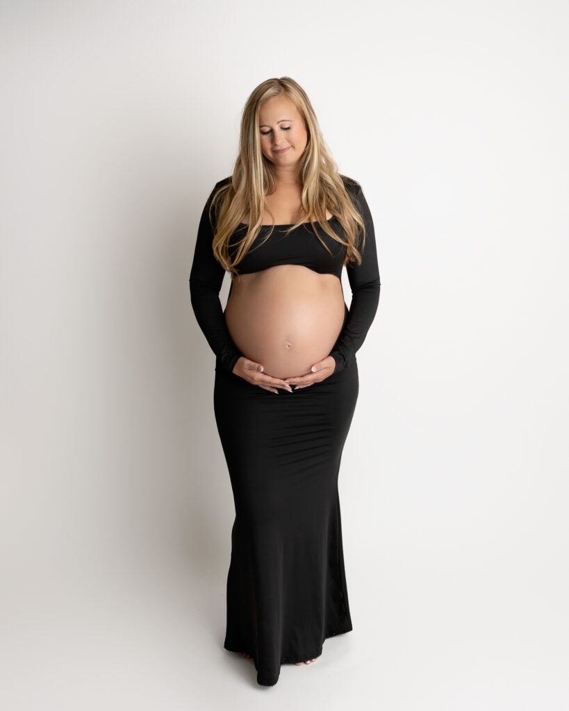 Maternity portrait of expecting mother cradling her belly in studio with neutral background before visiting an akron pediatrician.