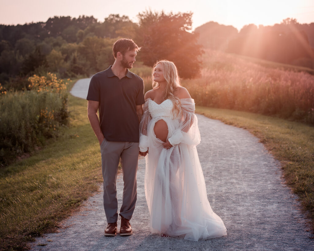 Canton Ohio maternity photographer capturing expecting couple walking at sunset during outdoor maternity session.