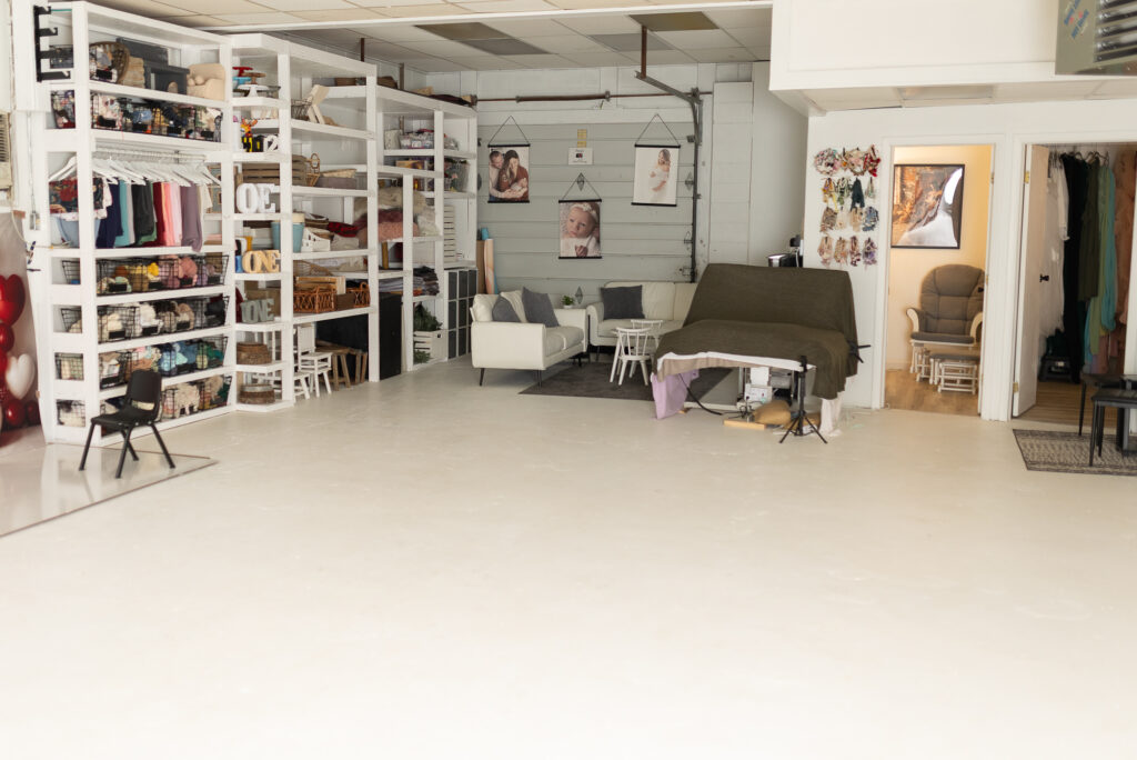 Spacious newborn photography studio with props, seating area, and posing setup