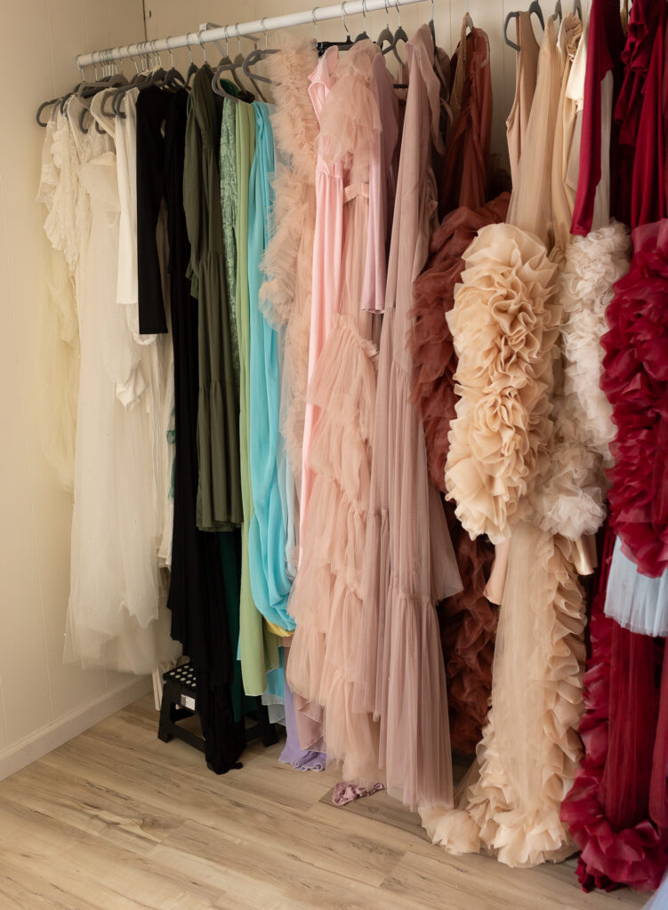 Client wardrobe rack filled with flowing dresses and gowns inside photography studio
