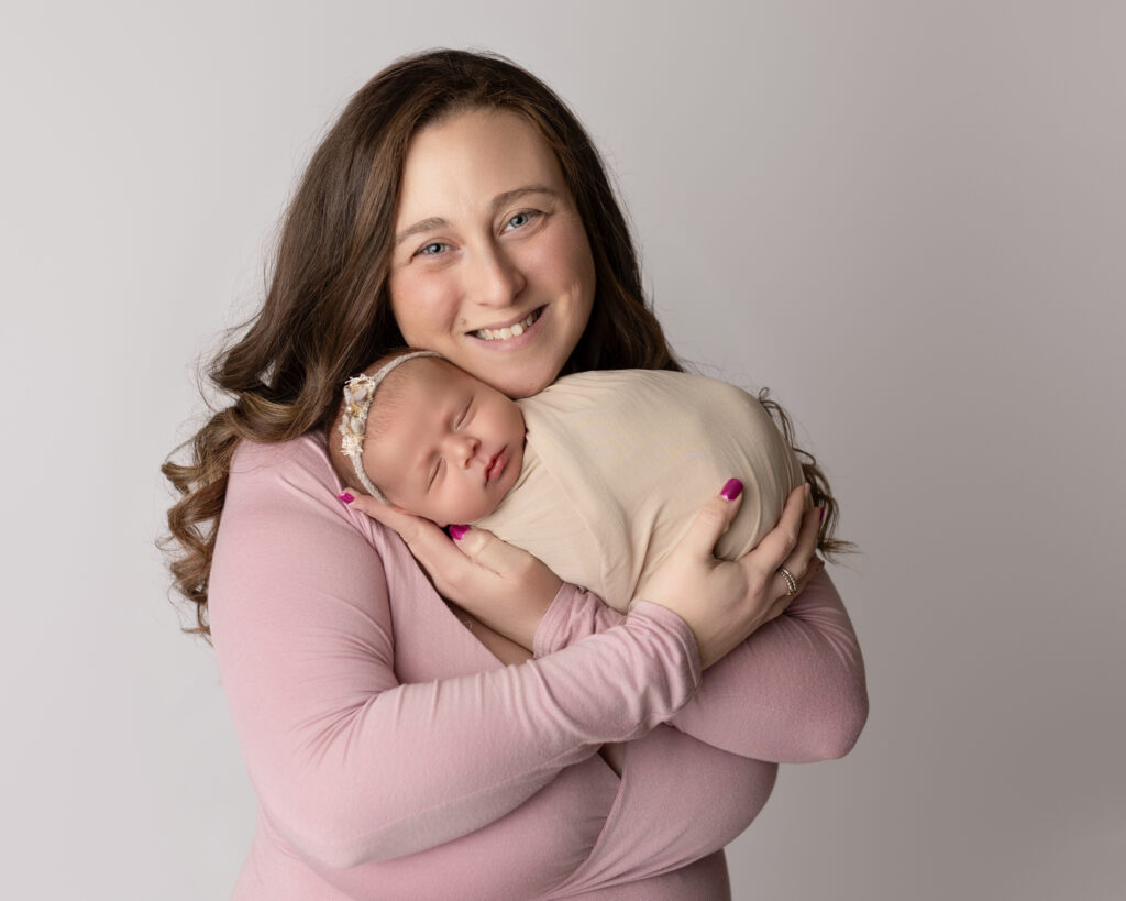 what to wear for newborn photos mom holding baby in neutral pink outfit